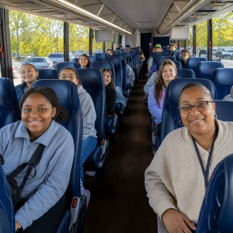Group boarding a white charter bus for School Transportation transportation in New Orleans